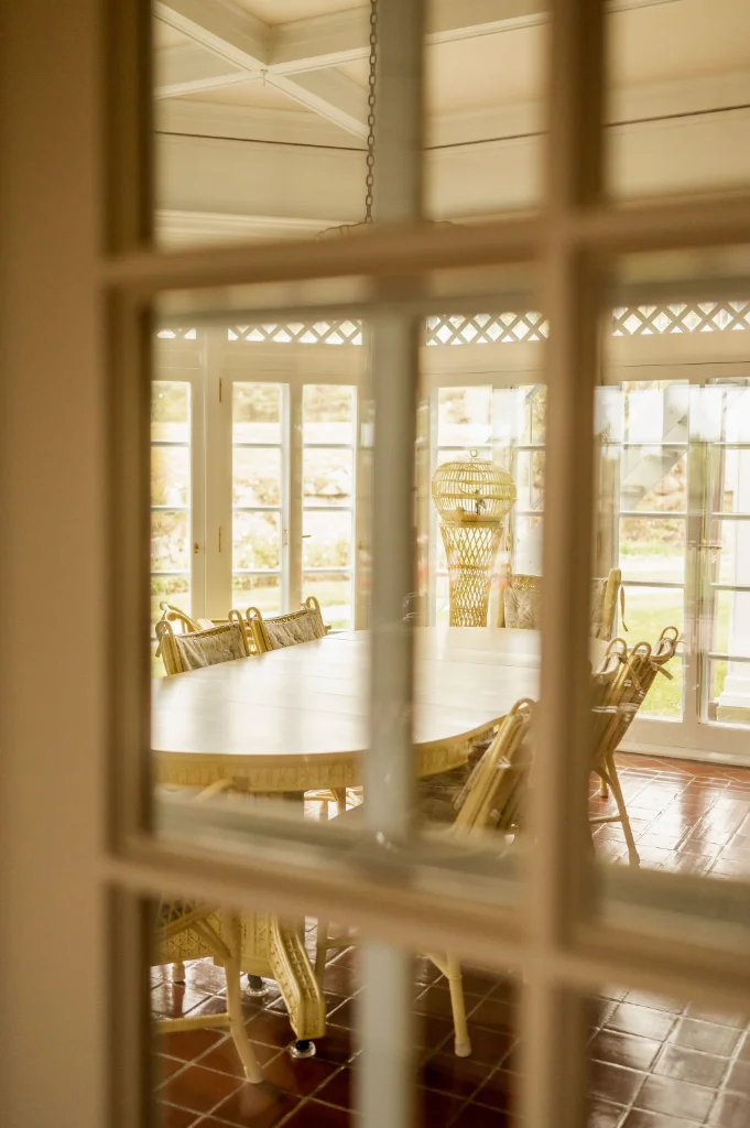 A large oval dining table inside a room with lots of windows